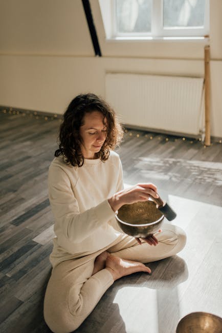 Woman practicing yoga indoors in a peaceful setting with soft light.